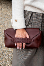 Een elegante bordeauxkleurige leren clutch die iedere outfit een stijlvolle en luxueuze uitstraling geeft. De diepe bordeauxkleur is tijdloos en prachtig te combineren met zowel neutrale tinten als warme herfstkleuren.