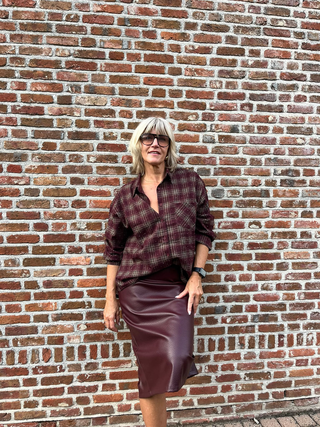 Dit prachtige bordeaux geruite hemd is een echte eyecatcher. Het tijdloze ruitpatroon krijgt een vrouwelijke en feestelijke twist dankzij de subtiele strassdetails, die het hemd net dat beetje extra geven.