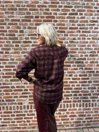 Dit prachtige bordeaux geruite hemd is een echte eyecatcher. Het tijdloze ruitpatroon krijgt een vrouwelijke en feestelijke twist dankzij de subtiele strassdetails, die het hemd net dat beetje extra geven.