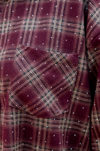 Dit prachtige bordeaux geruite hemd is een echte eyecatcher. Het tijdloze ruitpatroon krijgt een vrouwelijke en feestelijke twist dankzij de subtiele strassdetails, die het hemd net dat beetje extra geven.