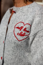 Dit mooie lichtgrijze vest is een tijdloos en veelzijdig item dat moeiteloos in elke garderobe past. Het rode, geborduurde hartje op de borst geeft het vest een speelse en vrouwelijke uitstraling.