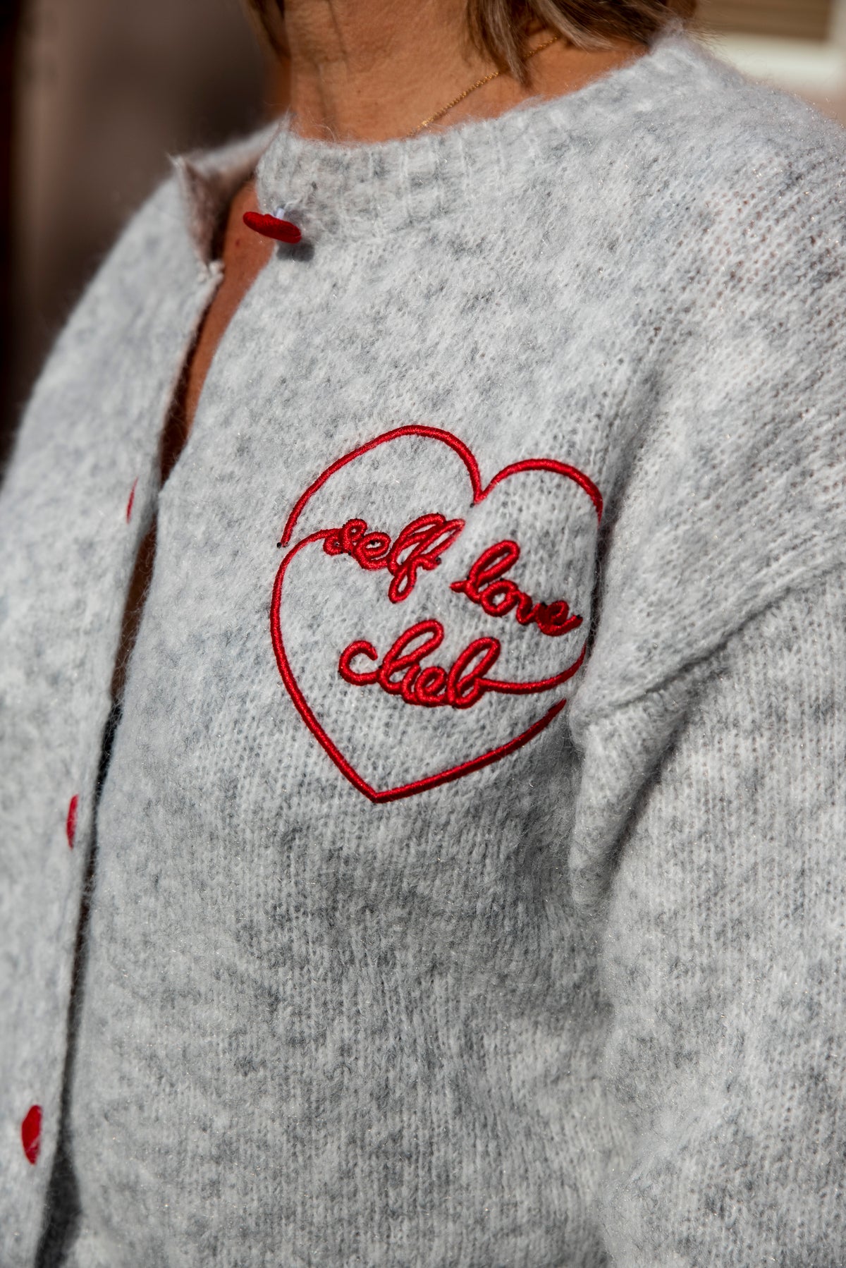 Dit mooie lichtgrijze vest is een tijdloos en veelzijdig item dat moeiteloos in elke garderobe past. Het rode, geborduurde hartje op de borst geeft het vest een speelse en vrouwelijke uitstraling.