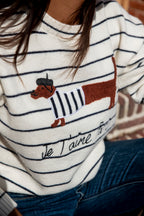 Deze heerlijke trui is niet alleen comfortabel, maar vooral ook ontzettend schattig. De blauwe streep geeft de trui een frisse, tijdloze uitstraling, terwijl het teckeltje voor een speels en uniek detail zorgt.