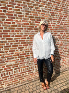 Dit mooie witte hemd is een echte must-have voor je garderobe. De klassieke, frisse uitstraling van het witte katoen wordt extra vrouwelijk dankzij het fijne kanten detail onderaan.