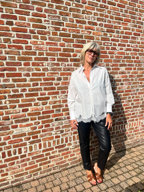 Dit mooie witte hemd is een echte must-have voor je garderobe. De klassieke, frisse uitstraling van het witte katoen wordt extra vrouwelijk dankzij het fijne kanten detail onderaan.